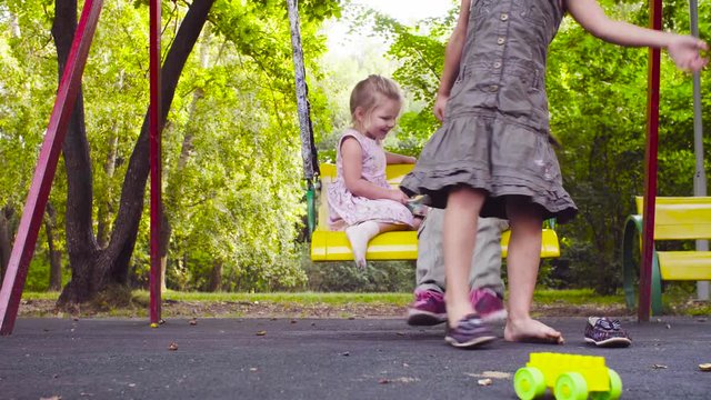 Low angle view. Two sisters get up from the swing and put on their shoes