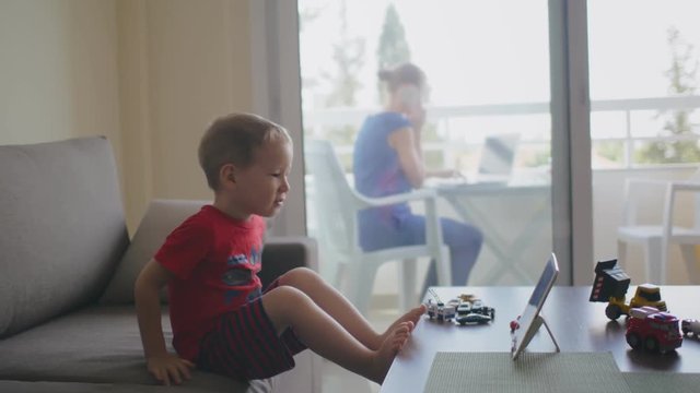 Baby is busy playing with toys while mom is working