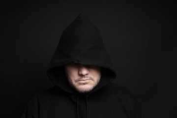 man wearing black hoodie hiding eyes in the dark                          