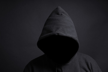 faceless person wearing black hoodie hiding face in shadow