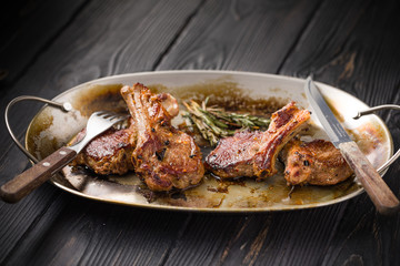 Lamb chops on a metal rustic plate with rosemary and spices