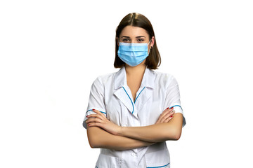 Woman doctor in face mask on white background. Beautiful female doctor with arms crossed, portrait.