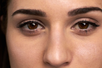 Close up open female eyes. Macro shot of pretty woman face with brown eyes. Feminine beauty concept.