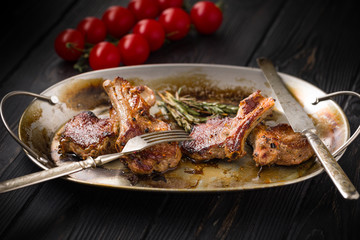 Lamb chops on a metal rustic plate with rosemary and spices