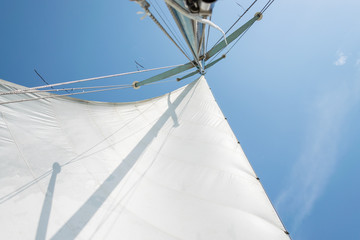Fototapeta premium White sail of a sailing boat against sky. Sails of river sailing yacht in the wind against the blue sky