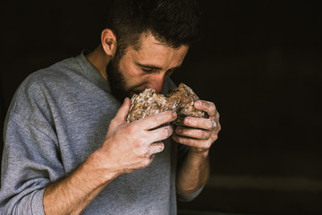 Close up of a young bearded man smelling delicious freshly baked bread