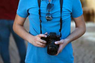 Close up, unrecognizable tourist man is holding an retro camera. Selective focus.