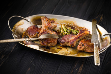 Lamb chops on a metal rustic plate with rosemary and spices