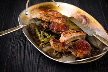 Lamb chops on a metal rustic plate with rosemary and spices