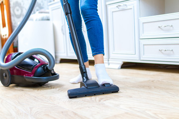 A vacuum cleaner. Room cleaning. Young woman cleaning the floor in the living room with a vacuum...