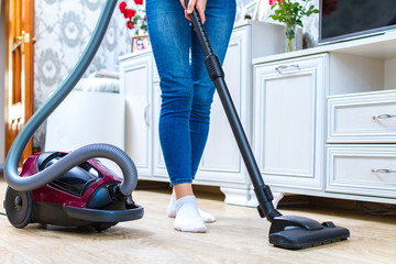 A vacuum cleaner. Room cleaning. Young woman cleaning the floor in the living room with a vacuum...