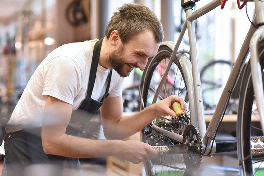 mechanic in a bicycle repair shop oiling the chain of a bike