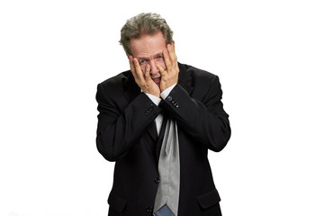 Depressed man covering his face by hands. Hopeless depressive businessman in black suit isolated on white background.