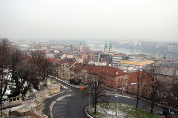 A view from the height of the observation deck of the Buda cities on the same bank of the Danube, and Pest on another remote bank of the Danube River against the background of the cloudy winter sky.