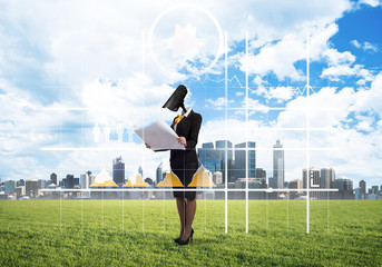 Camera headed woman standing on green grass against modern cityscape