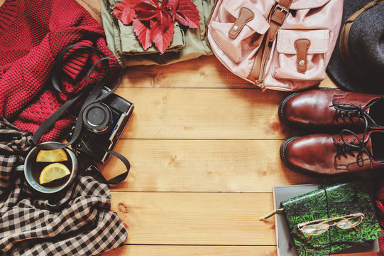 autumn women fashion clothes set with cozy sweater, shoes, plaid shirt, vintage photo camera, backpack and cup of tea. Fall seasonal walk concept, flat lay with empty space
