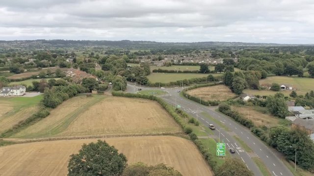 Aerial view, zoom and rise up move. Traffic on roundabout near Tarvin, town in Cheshire.