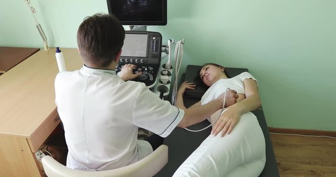 Male doctor examining the woman's left kidney using an ultrasound scanner.