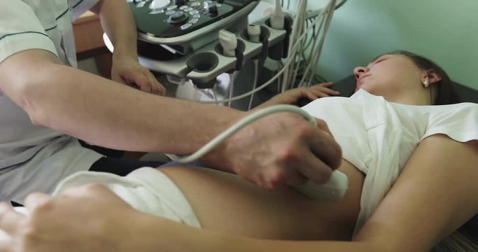 Doctor examining the woman's left kidney using an ultrasound scanner.