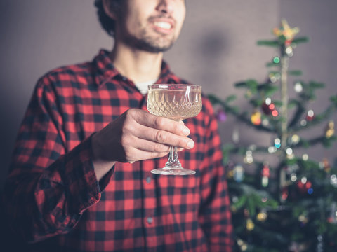 Happy man with drink by the christmas tree