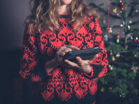 Woman using tablet by christmas tree