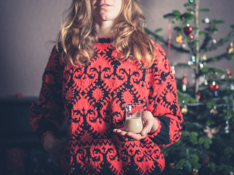 Woman with drink by christmas tree