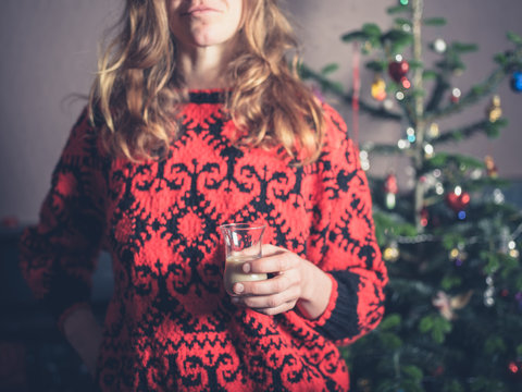 Woman with drink by christmas tree