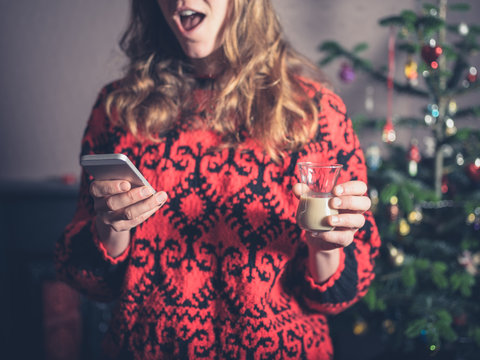 Woman with drink and smartphone at christmas