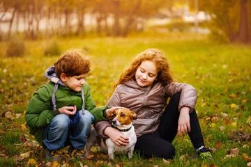 Fototapeta premium Little boy and girl with her puppy jack russell in autumn outdoors.