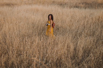 Young beautiful woman in yellow dress taking pictures with an old vintage camera. Countryside. Outdoors. Travel concept