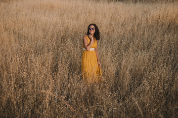 portrait of a Young beautiful woman in yellow dress looking at the camera and smiling. Countryside. Outdoors. Travel concept. Sunset