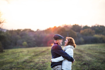 Senior couple hugging in an autumn nature at sunset.