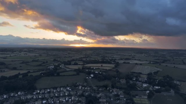 Aerial view, down move. Dramatic sky and sunset over residential buildings of small town, Tarvin in Cheshire.