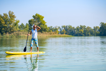 Fototapeta na wymiar Sporty man paddling on a SUP board on large river