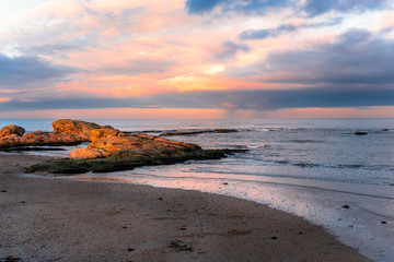 Orange Winter Sunset over a Deserted Sandy Beach with Sunlit Rocks. St. Andrews, Scotland