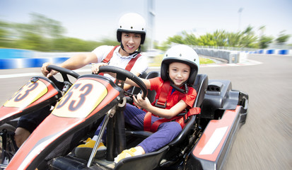father and daughter driving go kart on the track - obrazy, fototapety, plakaty