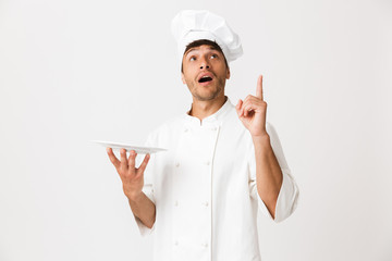 Chef man standing isolated over white wall background pointing to copyspace.