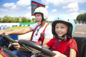 father and daughter driving go kart on the track - obrazy, fototapety, plakaty