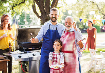 A mature man with family and friends cooking food on a barbecue party.