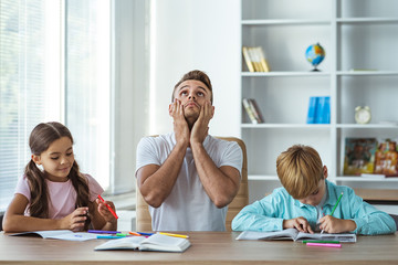 The father with kids doing homework at the desk