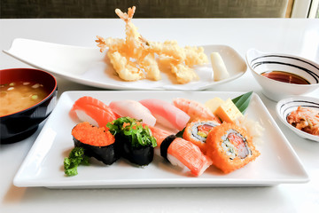 Closeup on authentic Japanese food lunch set of salmon sushi with shrimp tempura and miso soup on white table top background.