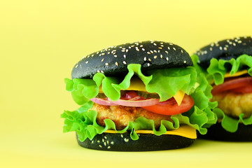 Fast food - juicy hamburgers on yellow background. Take away meal. Unhealthy diet concept with copy space