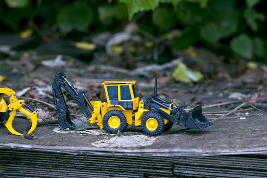 Two bulldozer grabbing on a layered wooden plank abandoned in nature.