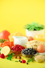 Vegan breakfast. Soft boiled egg, oat flakes, nuts, fruits, berries, milk, yogurt, orange, banana, peach on yellow background. Healthy food diet. Copy space. Banner