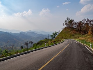 Road beside a valley with sun ray.