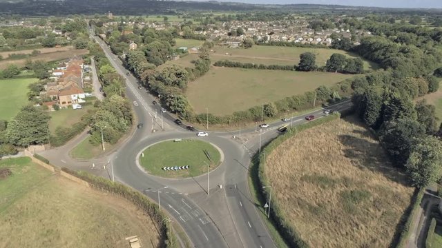 Aerial view, rise up move. Traffic on roundabout near Tarvin, small town among cheshire plains
