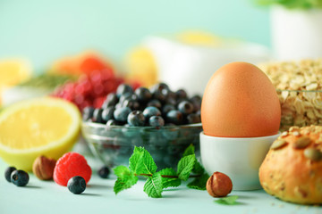 Breakfast served with soft boiled egg, oat flakes, nuts, fruits, berries, milk, yogurt, orange, banana, peach on yellow background. Healthy food diet.