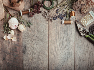 Florist equipment with flowers on wooden background, top view, rustic style