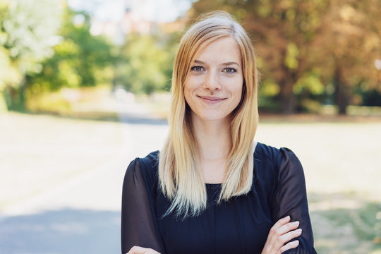 smiling young blond woman standing in city park