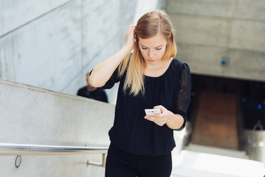 young woman with mobile phone in her hand walking upstairs 